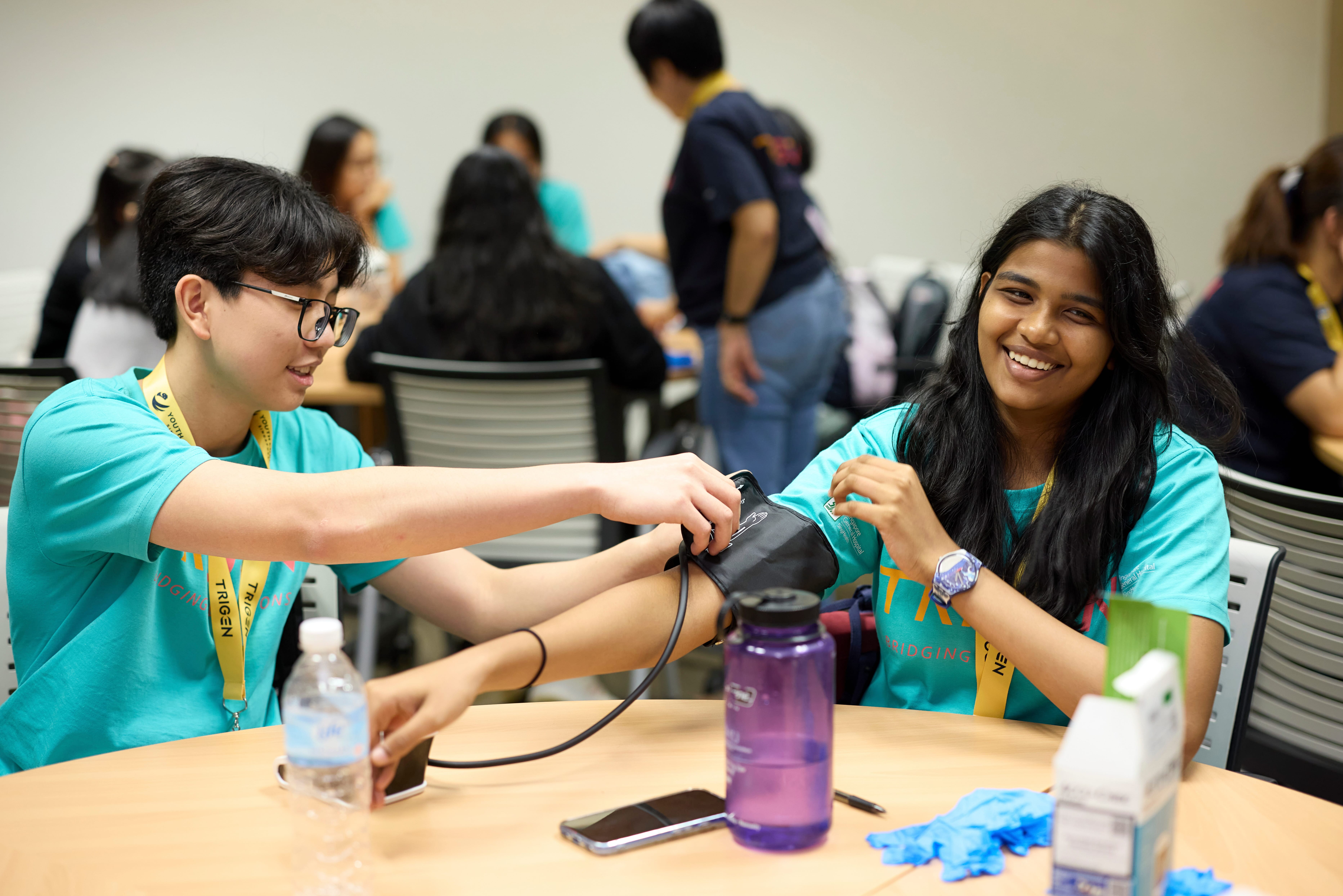 A guy helping a girl measure her blood pressure.